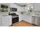 Updated kitchen features white cabinets, stainless appliances, and hardwood floors at 6979 Weasel Way, Evergreen, CO 80439