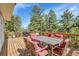Outdoor deck with dining furniture and forest views at 6979 Weasel Way, Evergreen, CO 80439