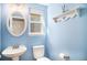 Bright powder bathroom with a vanity sink, commode, window, and decoratively painted blue walls at 16277 Blueleaf Pl, Parker, CO 80134