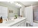 Well-lit bathroom featuring a double sink vanity and a tiled shower with glass doors at 8102 S Adams Fork Ave, Littleton, CO 80125