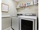 Functional laundry room with modern washer and dryer units and ample shelving space at 8102 S Adams Fork Ave, Littleton, CO 80125