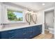 Elegant bathroom featuring dual sinks, vanity with blue cabinets and a large window at 10482 W 75Th Ave, Arvada, CO 80005