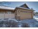 Attached garage with stone accents and snowy driveway at 8588 W Quarles Pl, Littleton, CO 80128