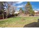 Beautifully landscaped backyard featuring mature trees and wooden fencing for privacy at 7923 S Marion Ct, Centennial, CO 80122