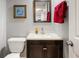 Powder room featuring a framed mirror, speckled countertop, dark cabinets and a red towel at 7923 S Marion Ct, Centennial, CO 80122