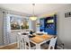 Dining room features a light wood table set for four near a window and a custom blue hutch at 7923 S Marion Ct, Centennial, CO 80122