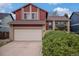 Two-story home featuring red wood siding and a brick-accented garage with manicured landscaping at 13339 E Idaho Pl, Aurora, CO 80012