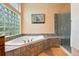 Bright bathroom featuring a glass block window above the tiled soaking tub and a separate glass-enclosed shower at 4944 W 107Th Loop, Westminster, CO 80031