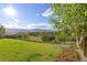 Beautiful backyard with lush green lawn, mature trees, and a split rail fence overlooking the valley at 444 Pasada Way, Monument, CO 80132
