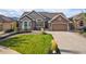 Inviting home features a well-manicured lawn, stone accents, an attached garage, and appealing curb appeal at 444 Pasada Way, Monument, CO 80132
