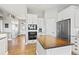 A spacious kitchen boasts stainless appliances, white cabinets, an island, and hardwood floors at 444 Pasada Way, Monument, CO 80132