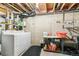 Unfinished basement laundry area with washer, dryer, utility sink, and storage shelves against a concrete wall at 1950 S Helena St # D, Aurora, CO 80013