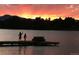 Two people enjoying the vivid sunset near a bench on the lake's pier at 5350 Yellowstone St, Bow Mar, CO 80123