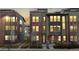 Attractive multi-story townhome at dusk boasts brick accents, large windows, and a well-maintained landscaped front yard at 8742 E 47Th Ave, Denver, CO 80238