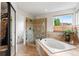 Spacious bathroom features a soaking tub, glass-enclosed shower, and large window for natural light at 6643 Orion Ct, Arvada, CO 80007