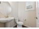 Well-lit half bathroom featuring a pedestal sink, white toilet, and natural light from the window at 11896 Meade Ct, Westminster, CO 80031
