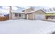 Tan house with a white garage door and snowy front yard at 16038 E Oxford Dr, Aurora, CO 80013