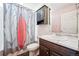 Well-lit bathroom featuring a vanity with marble countertop, stylish cabinet, and a unique feather-themed shower curtain at 20054 E 48Th Dr, Denver, CO 80249