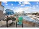 Outdoor deck with a grill and chair overlooking a neighborhood with homes, trees, and snow at 20054 E 48Th Dr, Denver, CO 80249