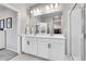 Elegant bathroom featuring dual sinks, white cabinets, a large mirror, a glass-enclosed shower, and a walk-in closet at 3086 Kestrel St, Brighton, CO 80601