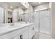 Elegant bathroom featuring dual sinks, white cabinets, a large mirror, and a glass-enclosed shower for a spa-like experience at 3086 Kestrel St, Brighton, CO 80601