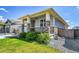 Home exterior with stone accents, a well-manicured lawn, and lush shrubbery at 3086 Kestrel St, Brighton, CO 80601