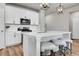 Bright kitchen with white cabinetry, stainless steel appliances, quartz countertops, and bar stool seating at the island at 3086 Kestrel St, Brighton, CO 80601