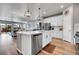 Open concept kitchen with island, white cabinets, stainless steel appliances, and seamless flow into living area at 3086 Kestrel St, Brighton, CO 80601