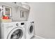 Well-lit laundry room featuring a modern front-load washer and dryer, and open shelving at 3086 Kestrel St, Brighton, CO 80601