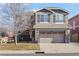 Two-story house with gray siding, a large driveway and landscaping at 4942 S Zephyr St, Littleton, CO 80123