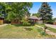 Brick home featuring mature trees, a well-kept lawn, and a welcoming front porch at 1475 Kingsbury Ct, Golden, CO 80401