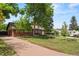 Brick ranch-style home with manicured front lawn, long driveway, and mature trees providing ample shade at 1475 Kingsbury Ct, Golden, CO 80401