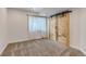 Carpeted bedroom with a natural wood sliding door, and a window with sheer white curtains at 19551 E Mann Creek Dr # B, Parker, CO 80134