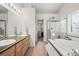 Bathroom featuring double sinks, large tub, and a glass shower enclosure at 5146 S Argonne St, Centennial, CO 80015