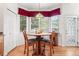 Cozy breakfast nook with a round table, three chairs, and a large bay window with red valances at 5146 S Argonne St, Centennial, CO 80015