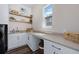 Bright laundry room featuring a sink, wooden shelves, and ample counter space with storage underneath at 2144 Bellcove Dr, Castle Pines, CO 80108