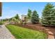 Landscaped backyard featuring a retaining wall, lush grass, and mature trees at 9781 Eagle River St, Littleton, CO 80125