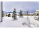 Snowy backyard with evergreen trees and distant houses at 1075 Whitekirk Pl, Castle Rock, CO 80104