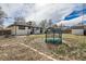 Backyard view featuring a trampoline, grassy area, fence, and partial view of the house at 327 S Xanadu St, Aurora, CO 80012