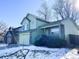 Two-story light green house with a two-car garage, snowy yard, and trees at 3802 Desert Willow Ave, Broomfield, CO 80020