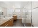 Bright bathroom featuring floating wood vanities, granite counters and a glass shower at 3930 Yates St, Denver, CO 80212