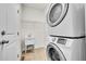 Functional laundry room equipped with a sink, storage shelf, and stacked washer and dryer at 10622 Racine St, Commerce City, CO 80022