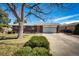 Brick home featuring a well-maintained lawn, mature trees, and attached two car garage at 1302 S Cape Way, Lakewood, CO 80232