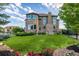 Beautiful backyard featuring a lush green lawn, stone and stucco exterior, and garden with colorful flowers at 15501 Fairway Dr, Commerce City, CO 80022