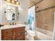 Bathroom featuring a stone countertop vanity, wood cabinets, shower-over-tub and decorative lighting at 15501 Fairway Dr, Commerce City, CO 80022