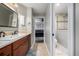 En-suite bathroom featuring tiled floors, dual access, and a vanity with stone countertop and dark wood cabinets at 15501 Fairway Dr, Commerce City, CO 80022
