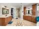 Large bathroom featuring double vanities, tile floors, and a glass enclosed shower at 15501 Fairway Dr, Commerce City, CO 80022