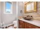 Stylish powder room featuring vessel sink, stone accent wall, and a decorative gold-framed mirror at 15501 Fairway Dr, Commerce City, CO 80022