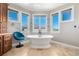 Bathroom with a freestanding tub, travertine tile floors, and three windows at 15501 Fairway Dr, Commerce City, CO 80022