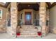 Inviting home entrance with stone pillars, a wooden door with windows, and landscaped steps at 15501 Fairway Dr, Commerce City, CO 80022